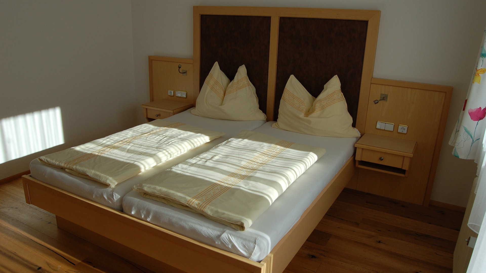 Modernes Schlafzimmer mit Doppelbett Helles Schlafzimmer mit einem Doppelbett, zwei großen Kissen und Holzfußboden. Minimalistische Einrichtung ist sichtbar.