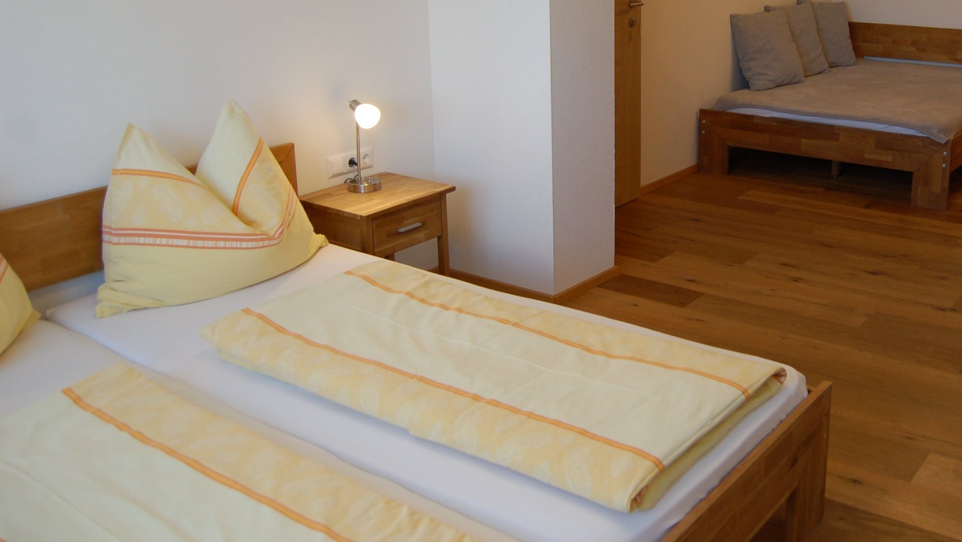 A bright bedroom with two wooden beds and yellow white bedding, showcasing modern interior design.