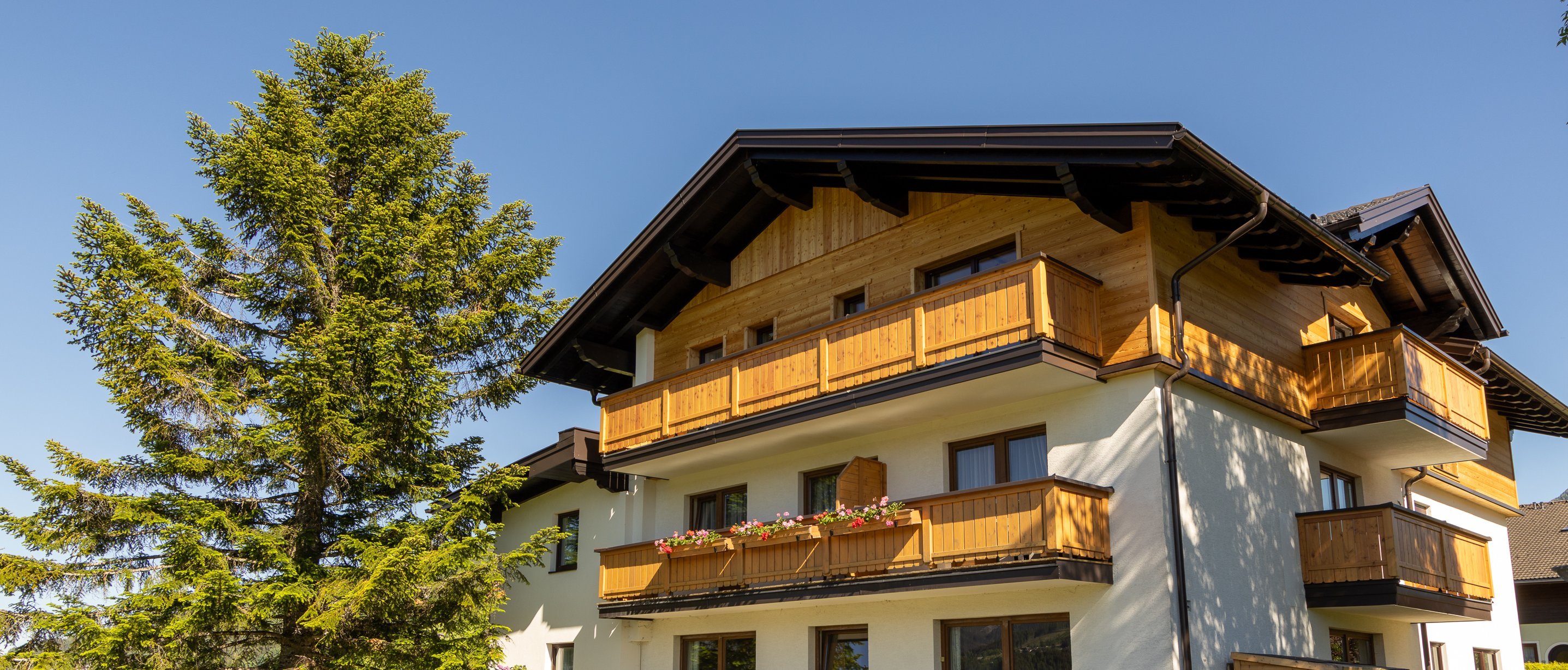Mountain Home with Scenic Balconies Multi-story house with wooden balconies set in a green landscape under a blue sky