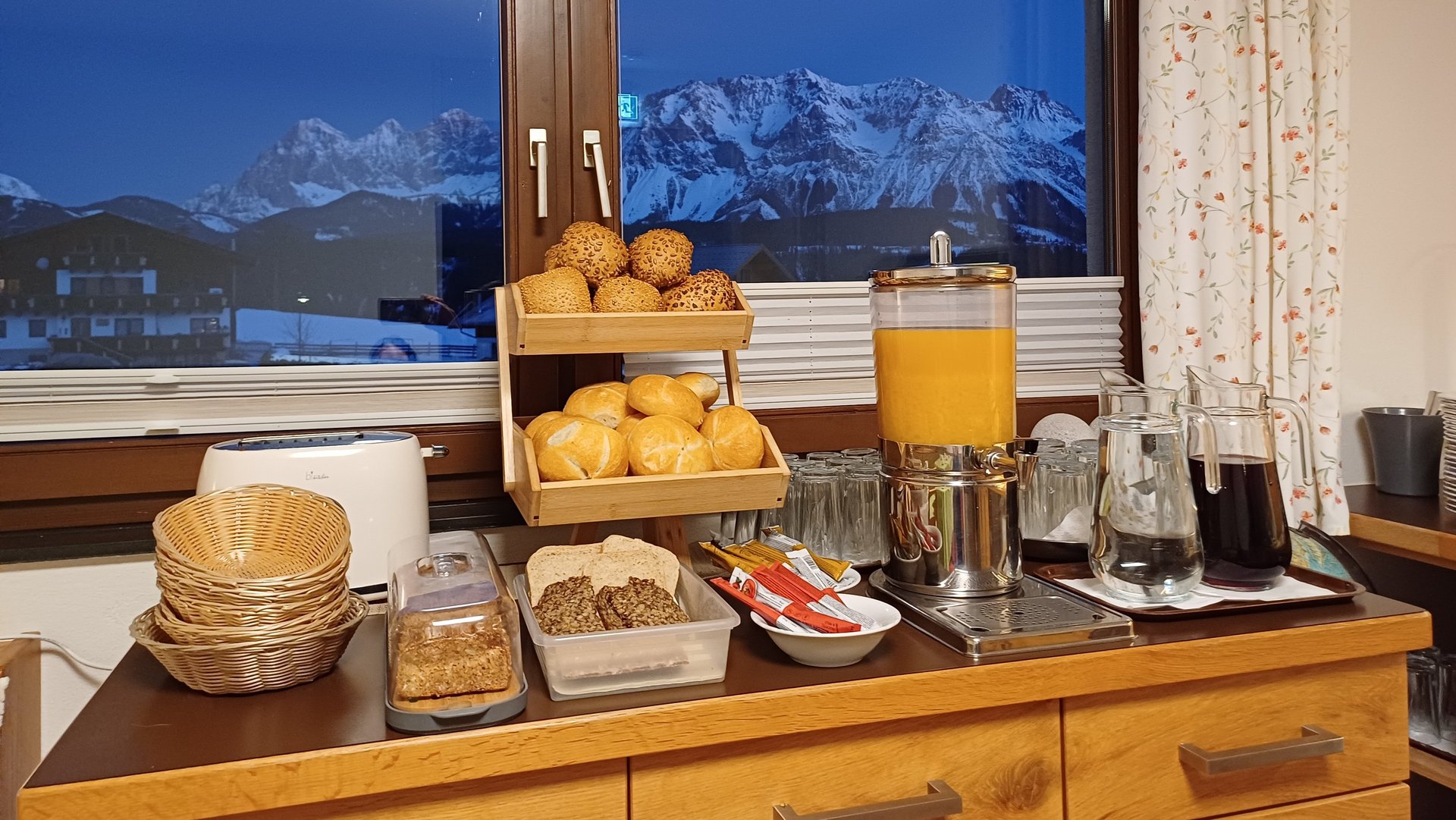Breakfast with a View A breakfast buffet featuring pastries and juices against a mountain backdrop through a window