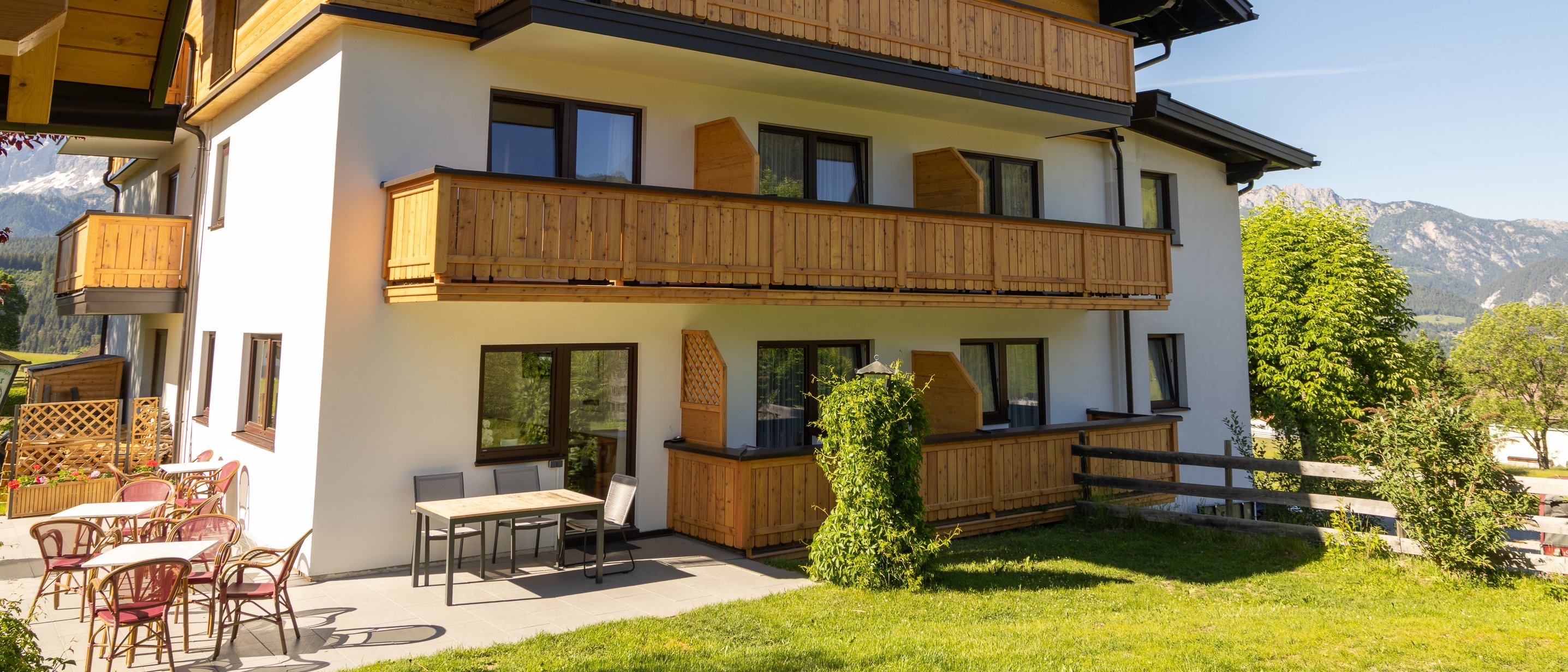 Contemporary mountain lodge featuring wooden balconies and outdoor seating areas surrounded by mountains