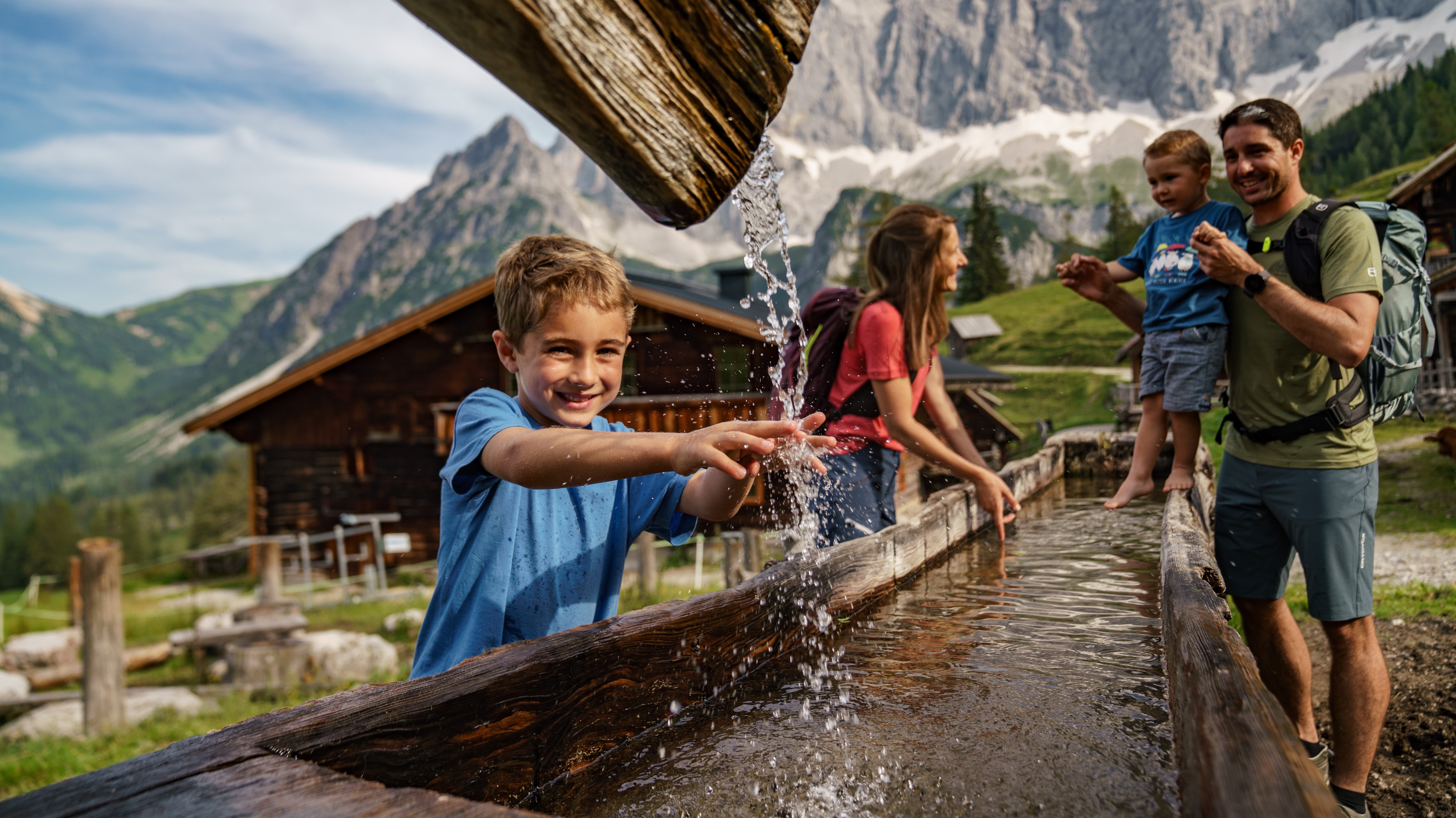 Family Fun in Nature A family with children playing in a water fountain surrounded by a mountainous landscape