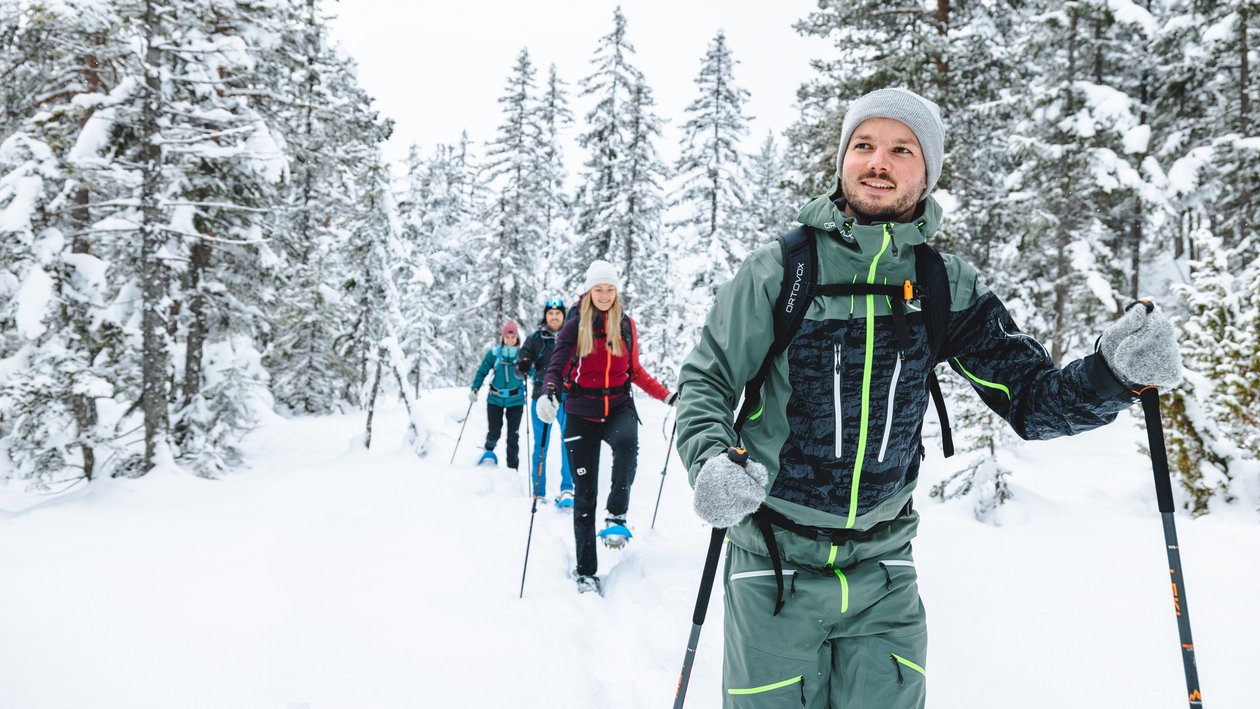 Gruppe von Menschen beim Schneeschuhwandern in verschneiter Landschaft mit Bäumen
