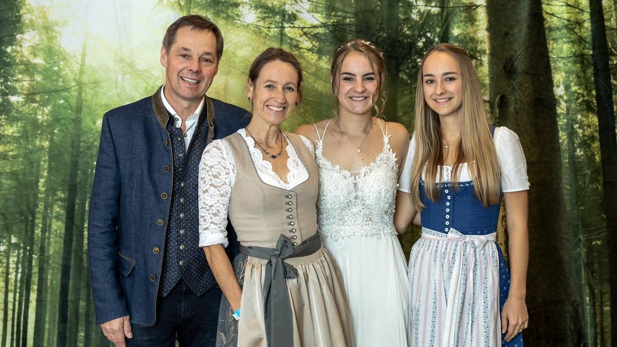 Eine Familie posiert in traditioneller Tracht vor einem Waldhintergrund.