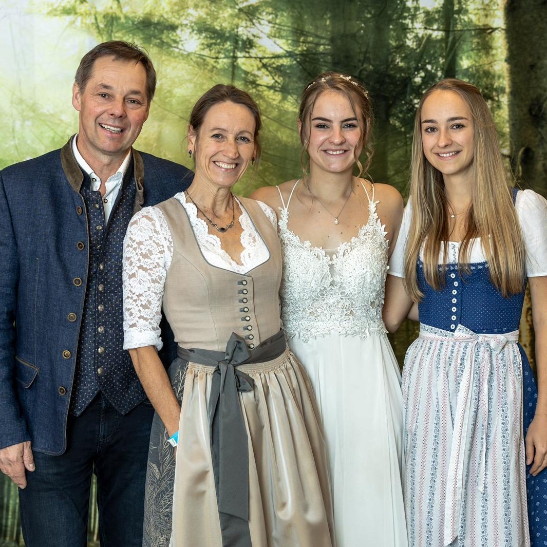 Eine Familie posiert in traditioneller Tracht vor einem Waldhintergrund.