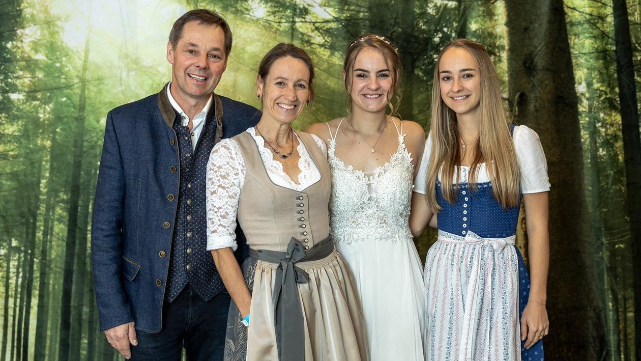 Eine Familie posiert in traditioneller Tracht vor einem Waldhintergrund.