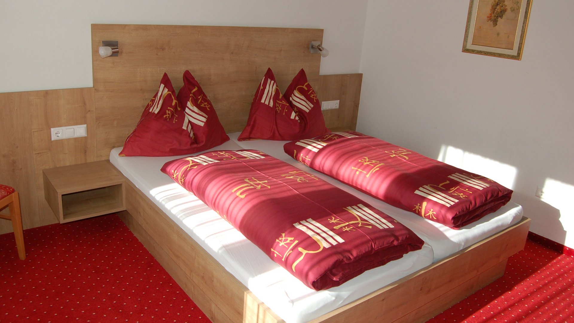 Hotel room with two beds, red bedding, and wooden furniture in modern design style