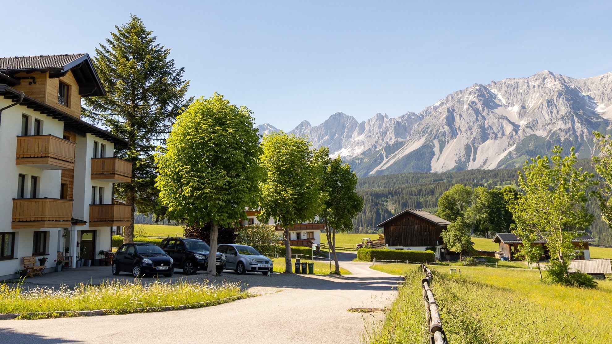 The Pension building nestled in a lush mountain landscape under clear blue skies with greenery