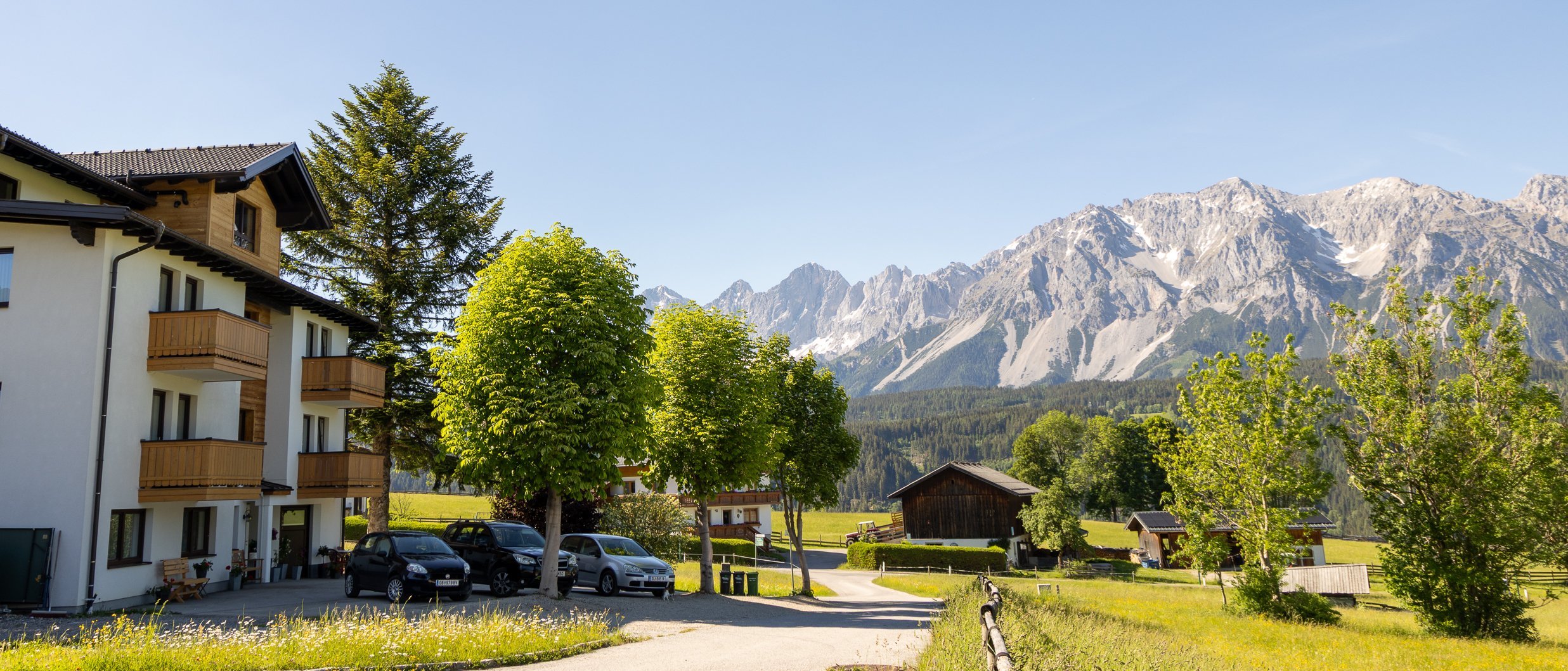 Hotelgebäude in einer malerischen Berglandschaft unter klarem blauen Himmel mit hohen Bergen im Hintergrund