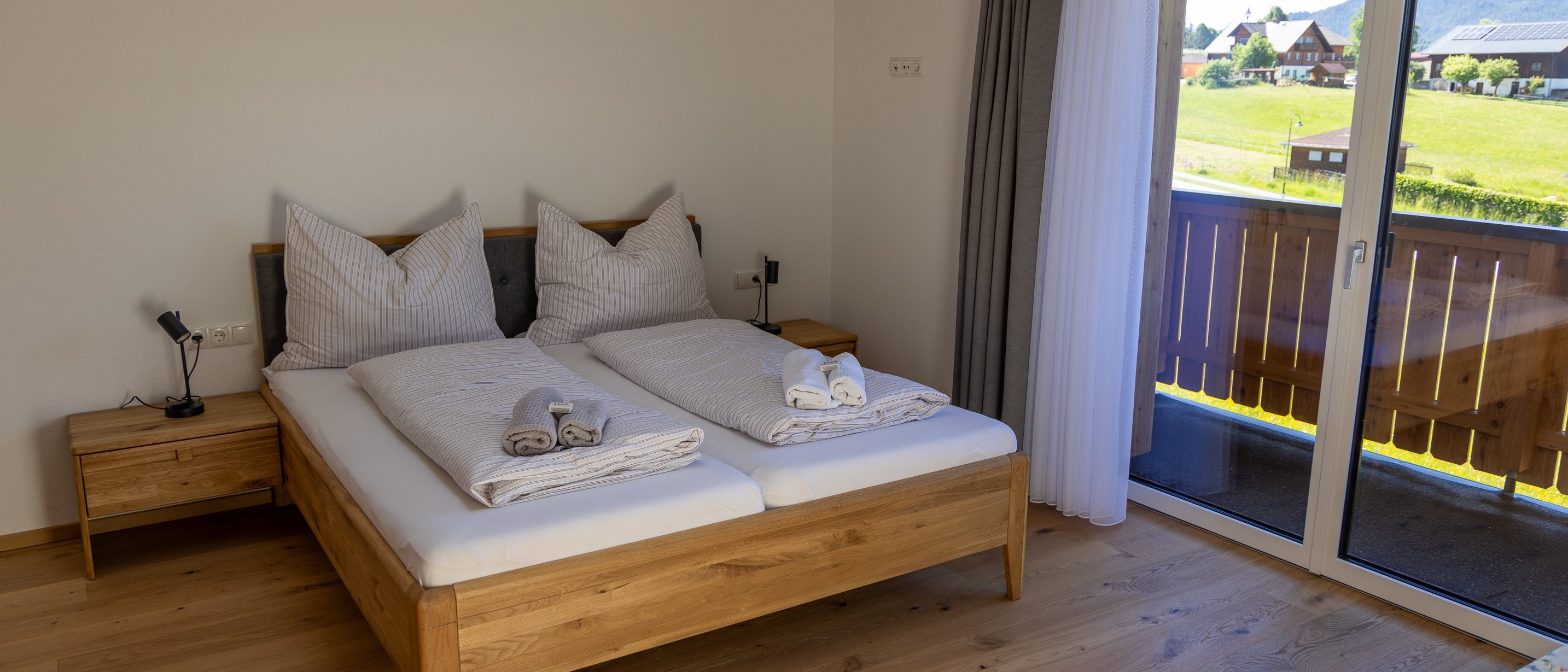 Komfortables Schlafzimmer mit Aussicht Schlafbereich mit Doppelbett, Holzmöbeln und Balkonzugang zu malerischer Landschaft