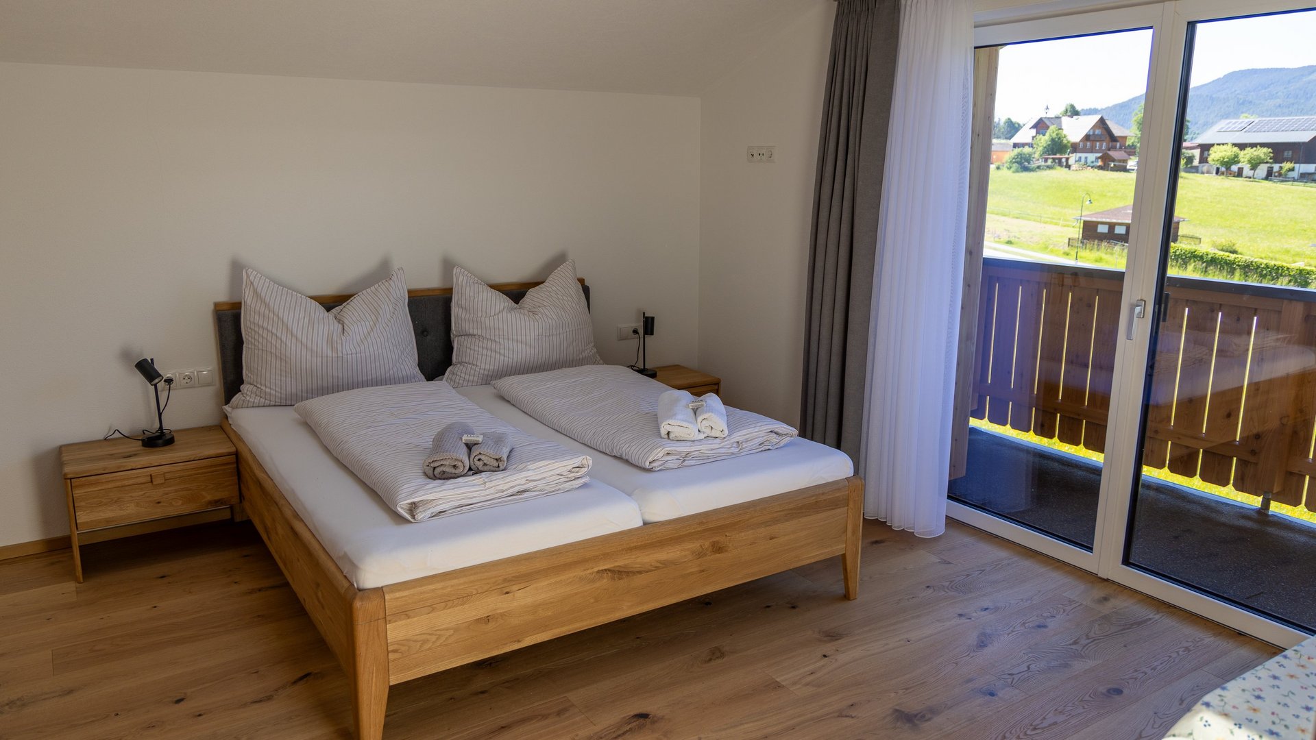 Komfortables Schlafzimmer mit Aussicht Schlafbereich mit Doppelbett, Holzmöbeln und Balkonzugang zu malerischer Landschaft