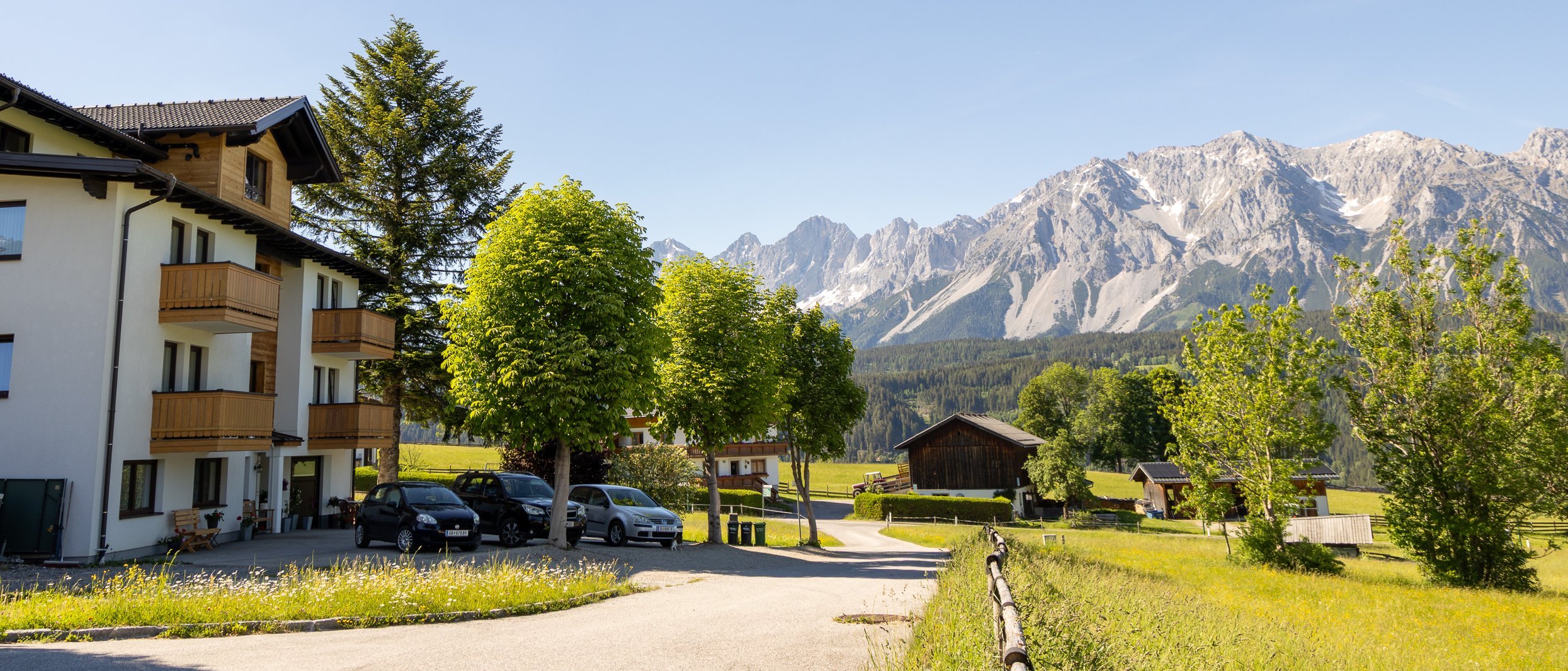 Hotelgebäude in einer malerischen Berglandschaft unter klarem blauen Himmel mit hohen Bergen im Hintergrund