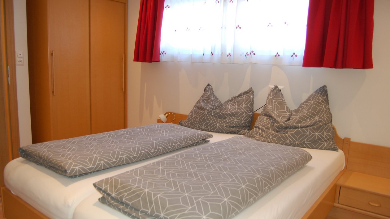 Helles Schlafzimmer mit zwei Einzelbetten und einem Kleiderschrank im Hintergrund.