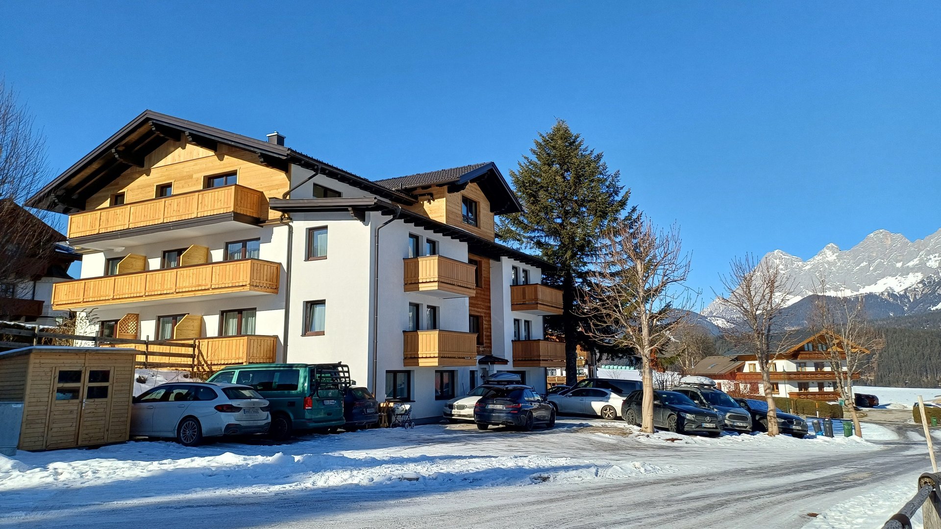 Modern Pension Fernblick in Schladming A contemporary lodge surrounded by a snowy landscape with parked cars in front and mountains behind
