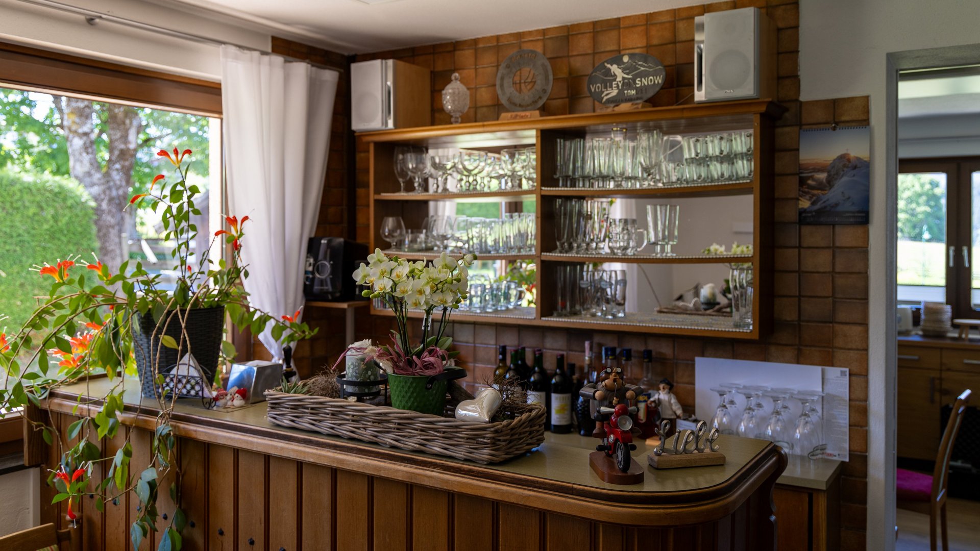 Stylish Home Bar Setup Home bar area with shelves displaying glassware, bottles and decorative plants for interior design