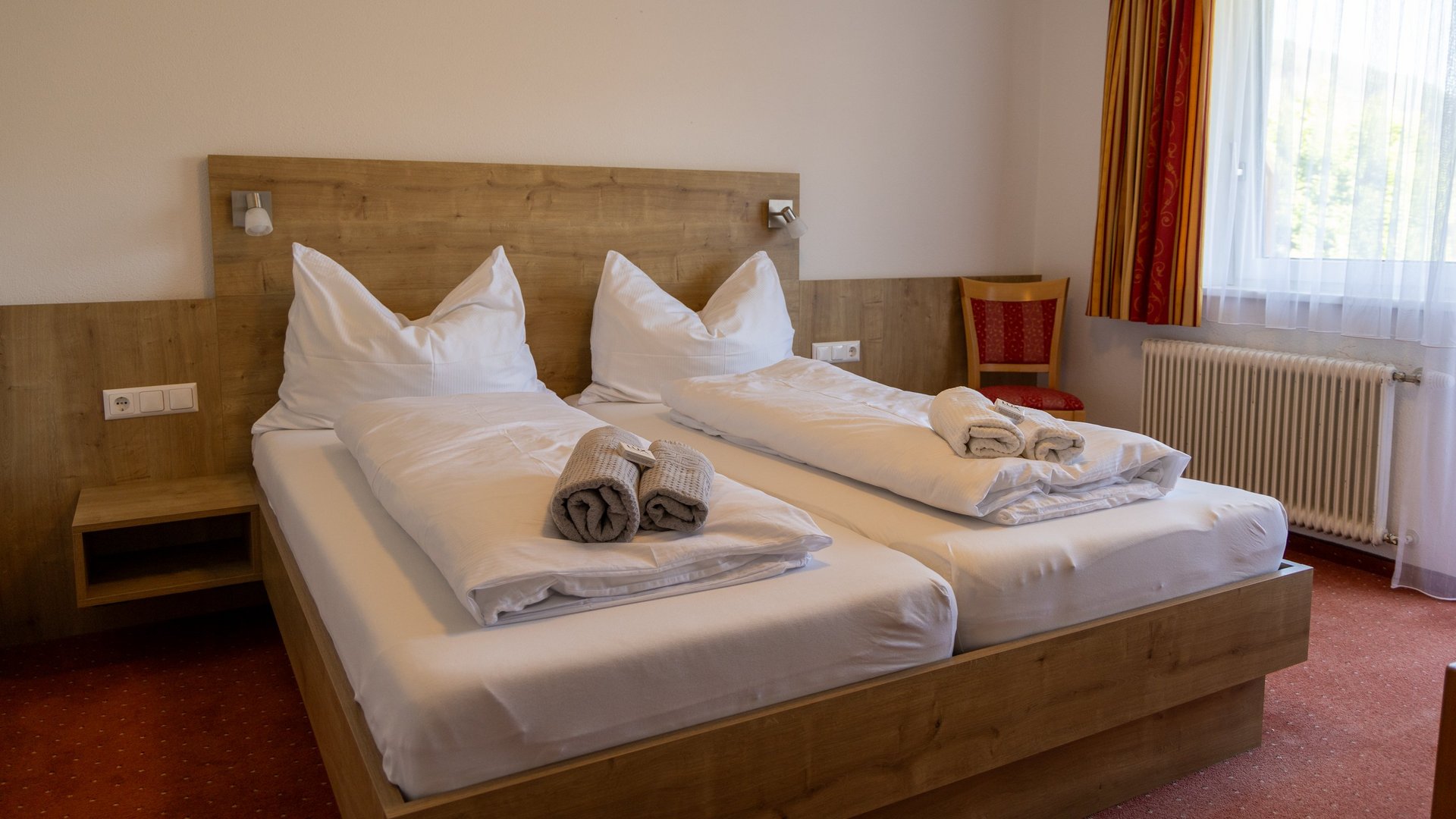 Helles Hotelzimmer mit zwei Betten und Holzinterieur, Fenster für Tageslicht, entspannende Atmosphäre